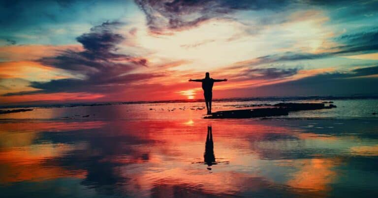 Person standing on beach watching sunset